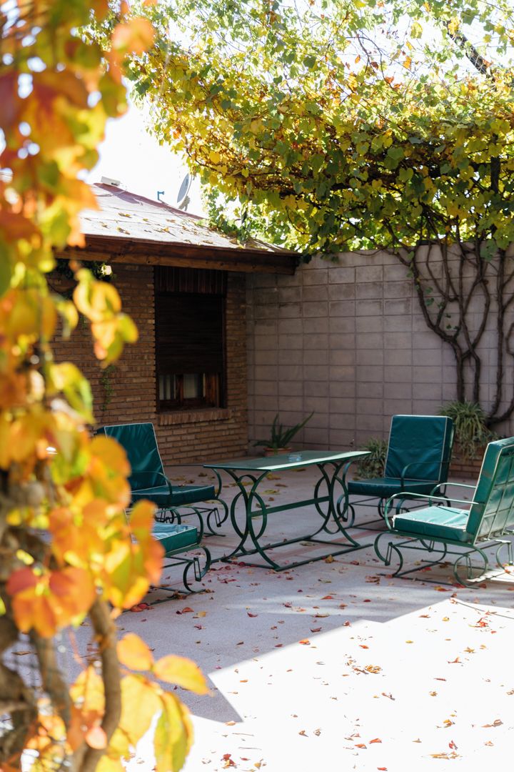 An outdoor patio area with a brick wall, a table, and two chairs.