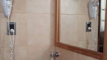 Un baño con lavamanos, espejo, secador de pelo y toallero.