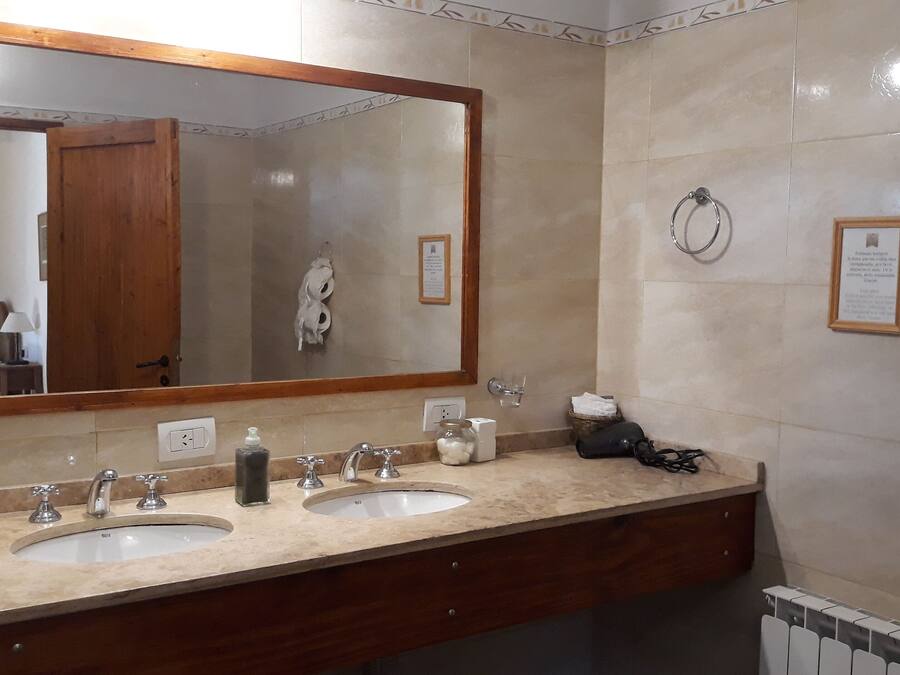 Baño con dos lavamanos, un espejo grande y un perchero para toallas.