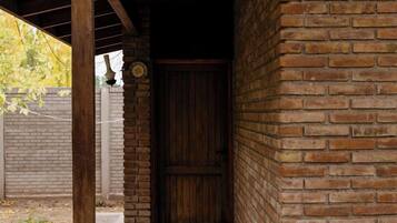A covered outdoor area with a brick wall, a wooden door, and a ceiling fan.