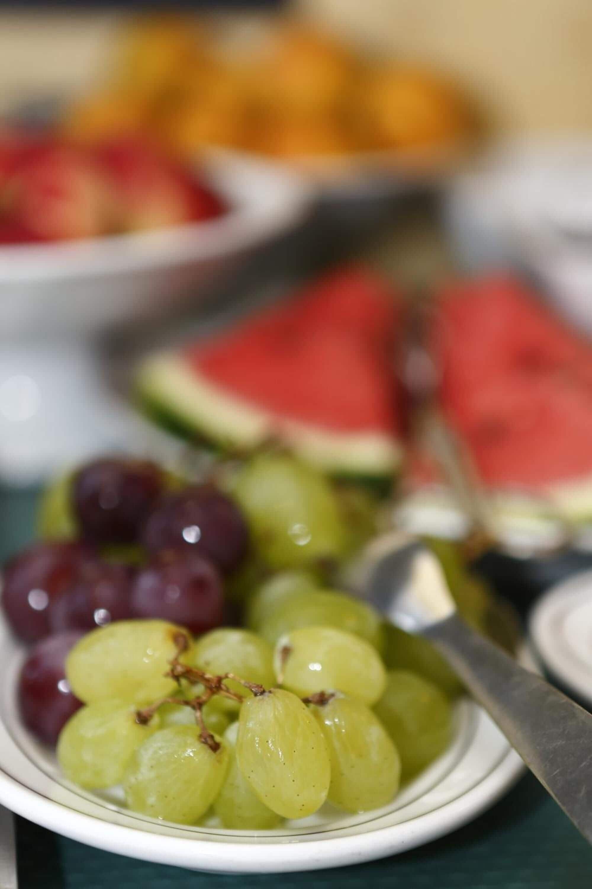 Une vue rapprochée d’un plateau de fruits contenant des raisins et des tranches de pastèque.