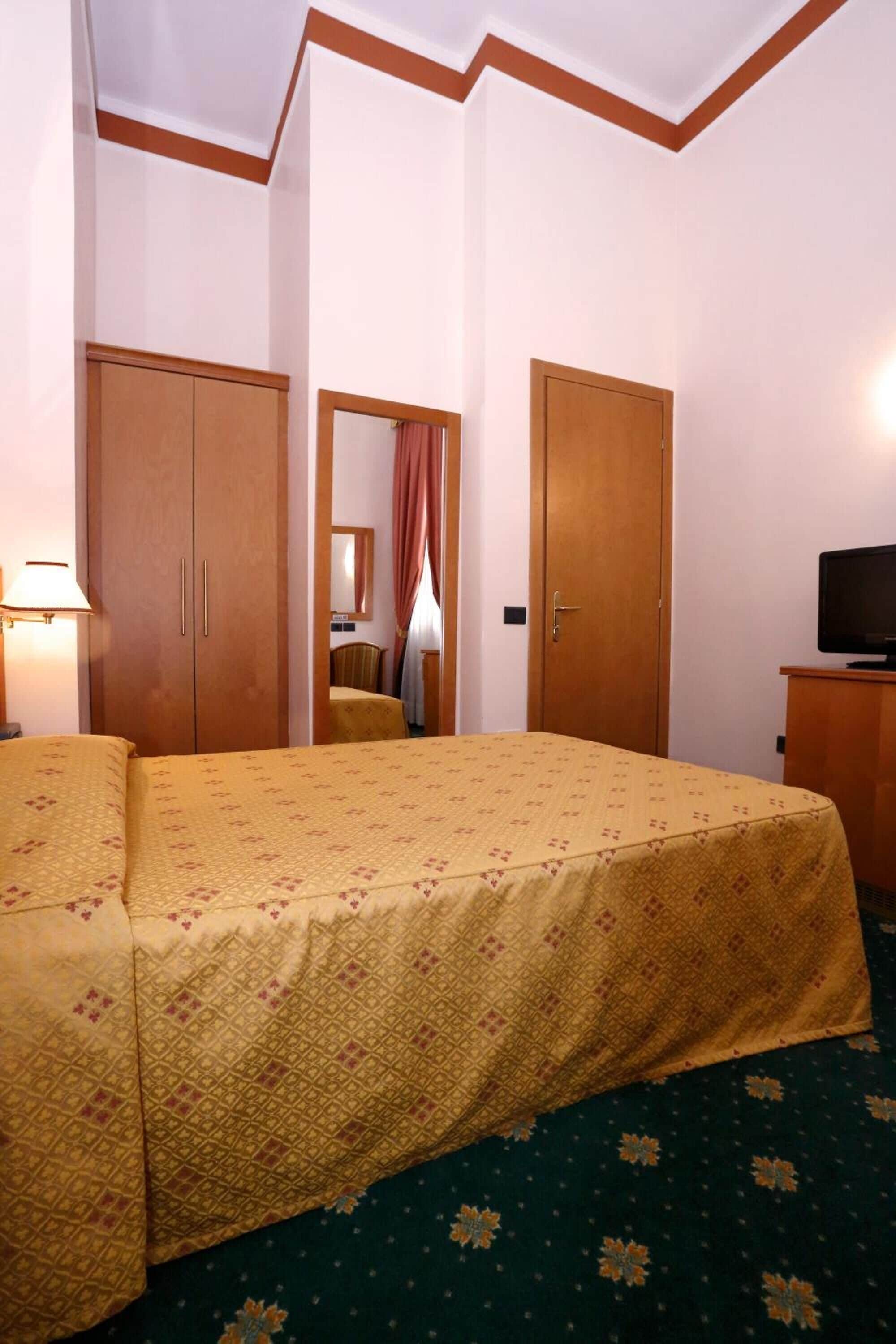 A hotel room with a bed, a television, and a wardrobe.