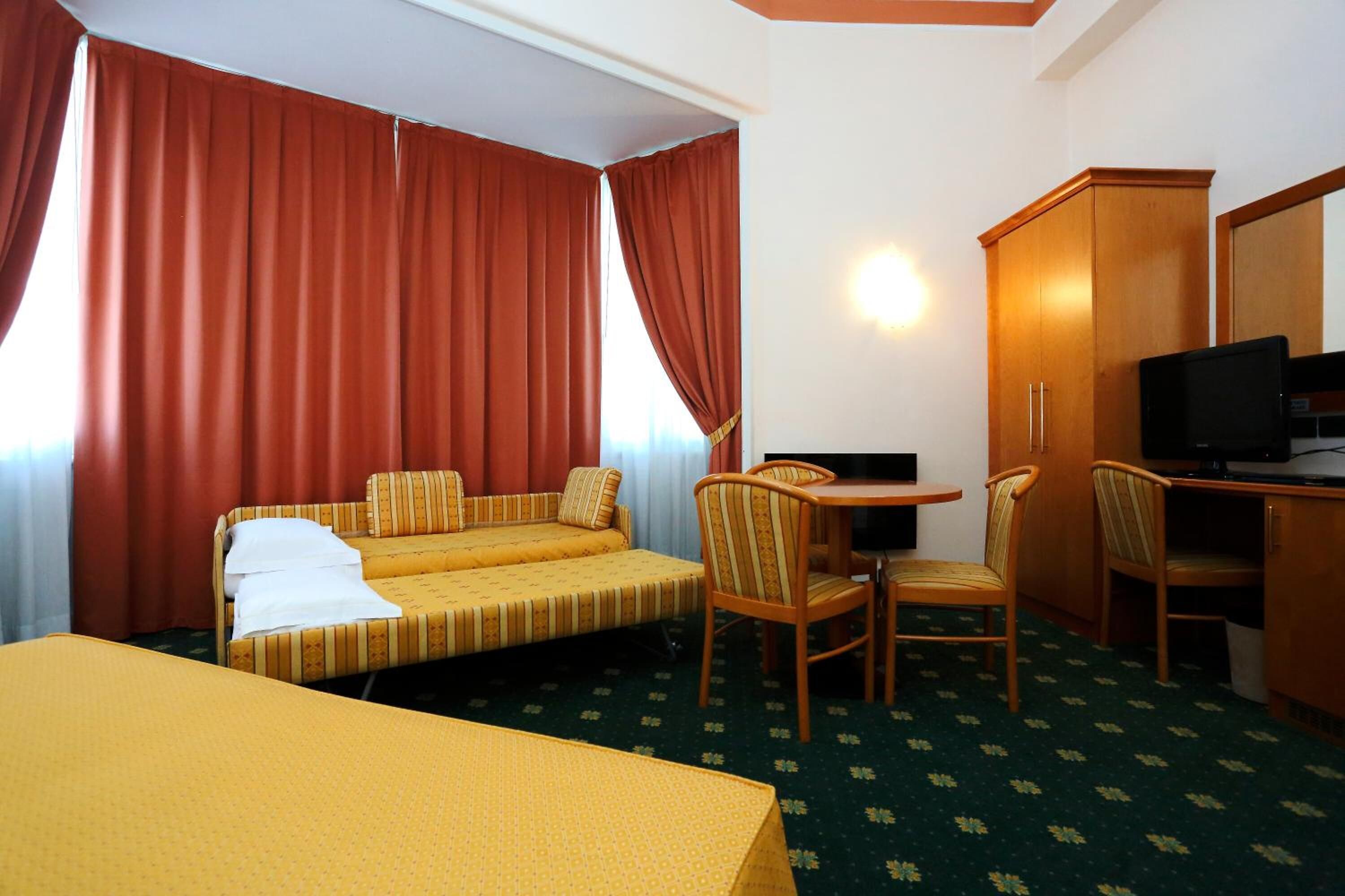 Une chambre d’hôtel comprenant un lit, un bureau avec une chaise, une télévision et une armoire.