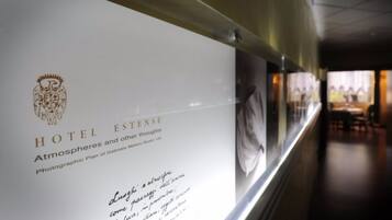 A corridor with a wall displaying a sign for Hotel Estense, mentioning a photographic plan by Gabrielle Melloni Studio 129.