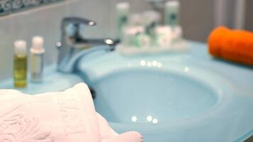 Un baño con un lavamanos azul, una toalla blanca y artículos de aseo.