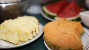 A table with plates of sliced pineapple and cantaloupe.