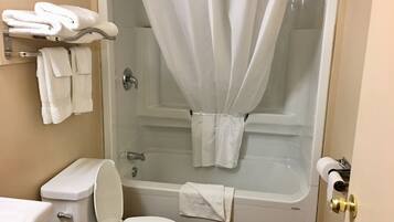 A bathroom with a toilet, a bathtub with a shower curtain, and a towel rack with towels.