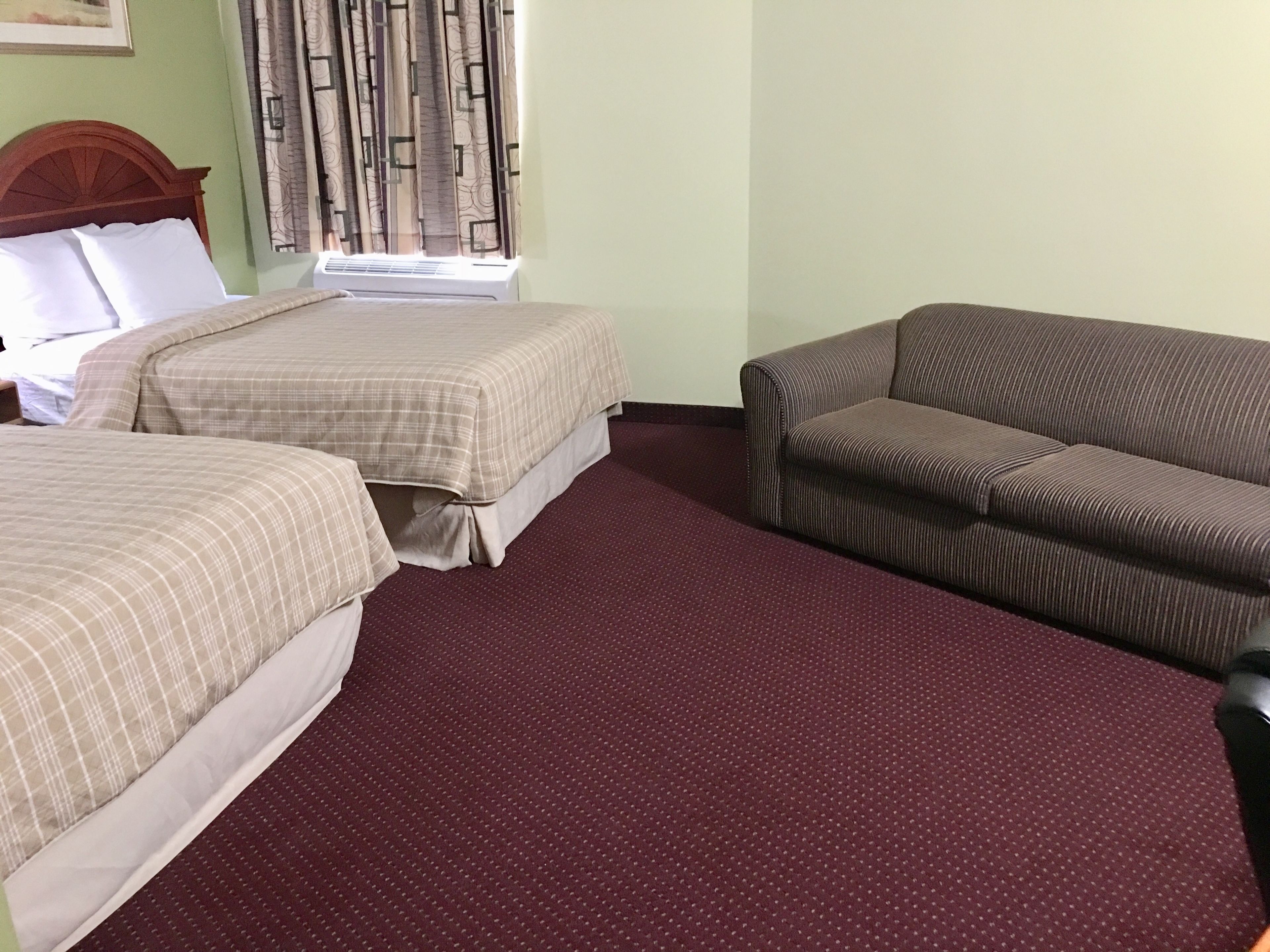 Habitación de hotel con dos camas, un sofá y una cortina estampada.