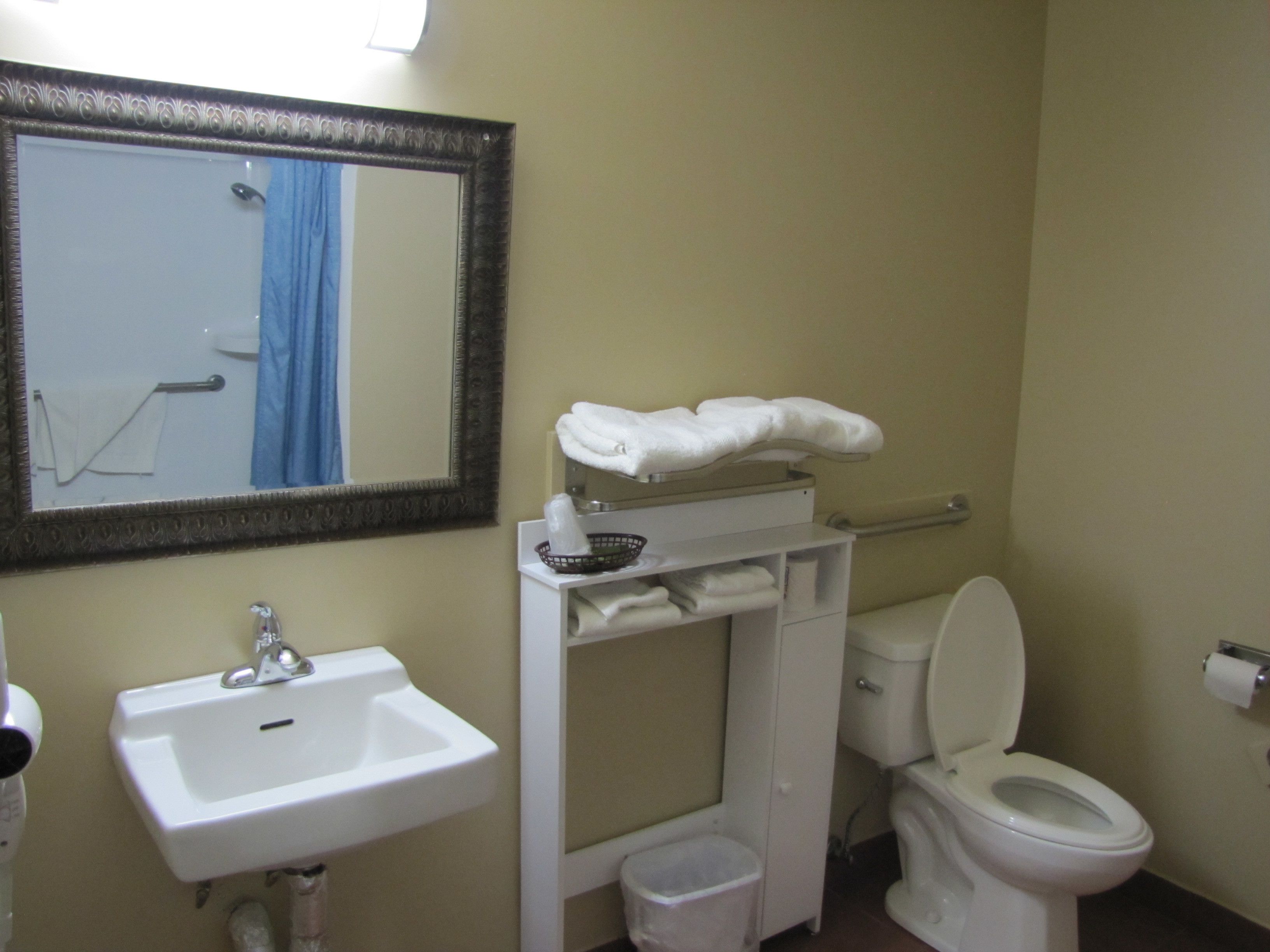 A bathroom with a sink, mirror, towel rack, and toilet.