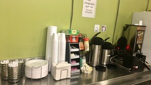 Una barra de desayuno con apiladas fuentes blancas, una tetera, una cafetera y condimentos.