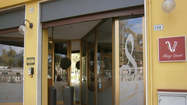 A hotel entrance with a glass door, a sign indicating the hotel name, and a number on the wall.