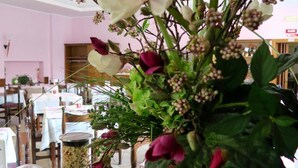 A dining area with tables, chairs, and a floral centerpiece.