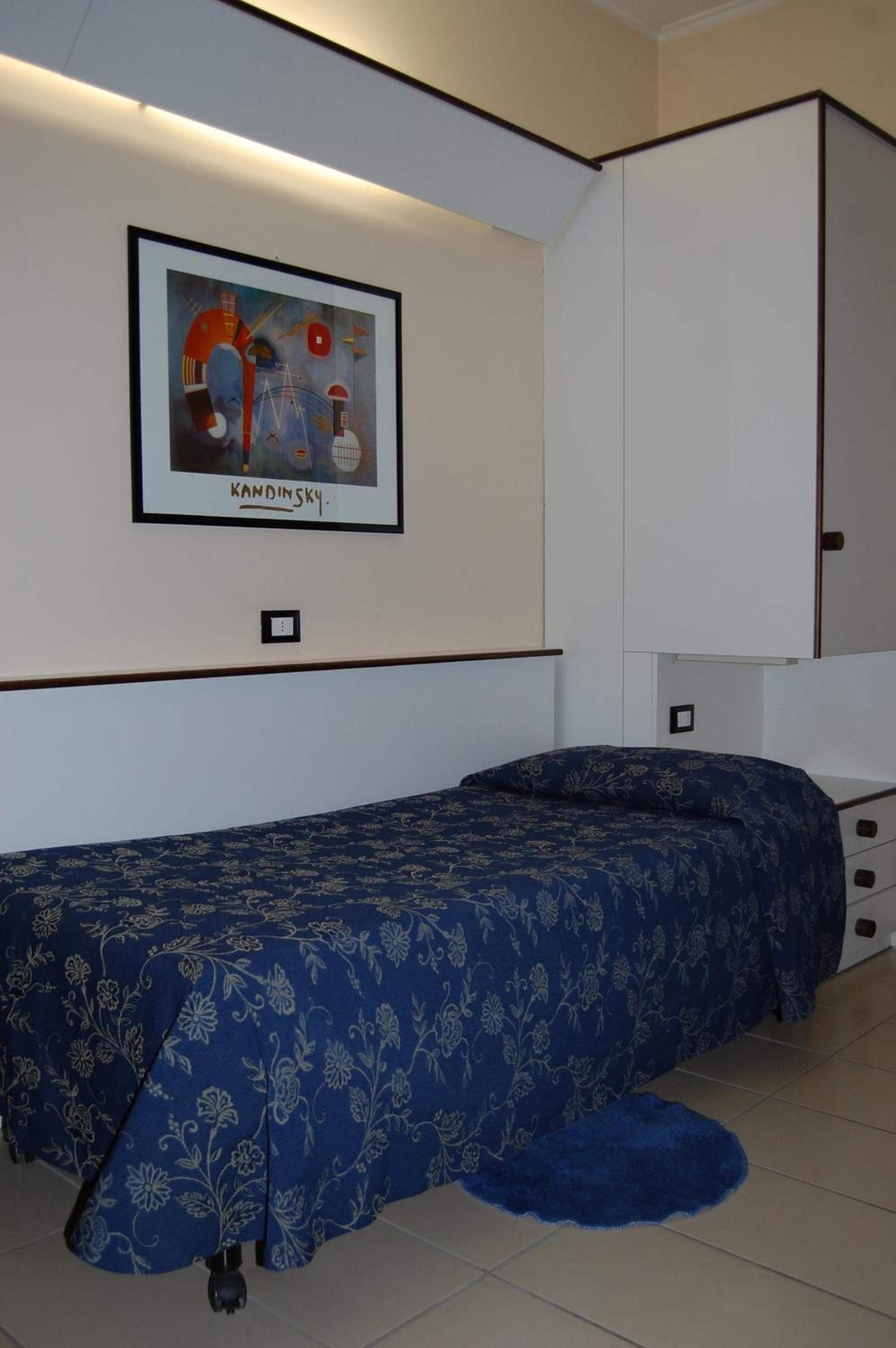 Una camera da letto con un letto, un quadro appeso al muro e un armadio.