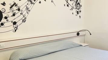 Un dormitorio con cama, mesita de noche y un diseño decorativo con temática musical en la pared.
