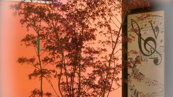 Una planta en maceta con flores moradas frente a una pared con un cuadro grande enmarcado.