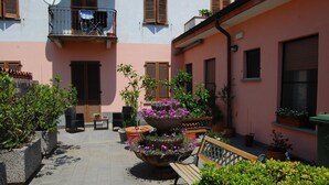 A courtyard with a bench, potted plants, and a multi-tiered flower pot.