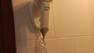 Un secador de pelo fijado a la pared, con un enchufe debajo.