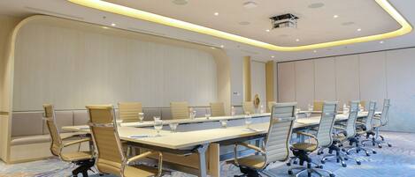 A conference room with a long table, multiple chairs, and a carpeted floor.