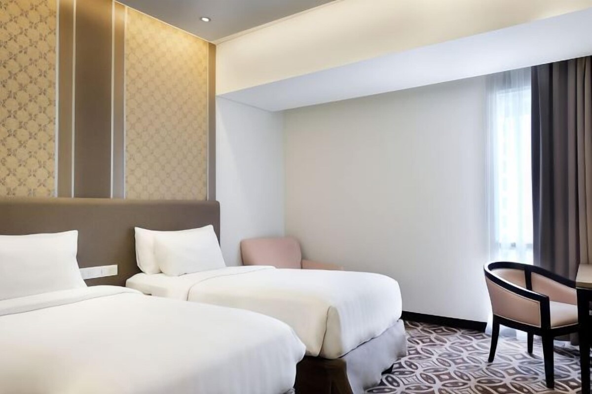 Una habitación de hotel con dos camas, un escritorio y una silla.
