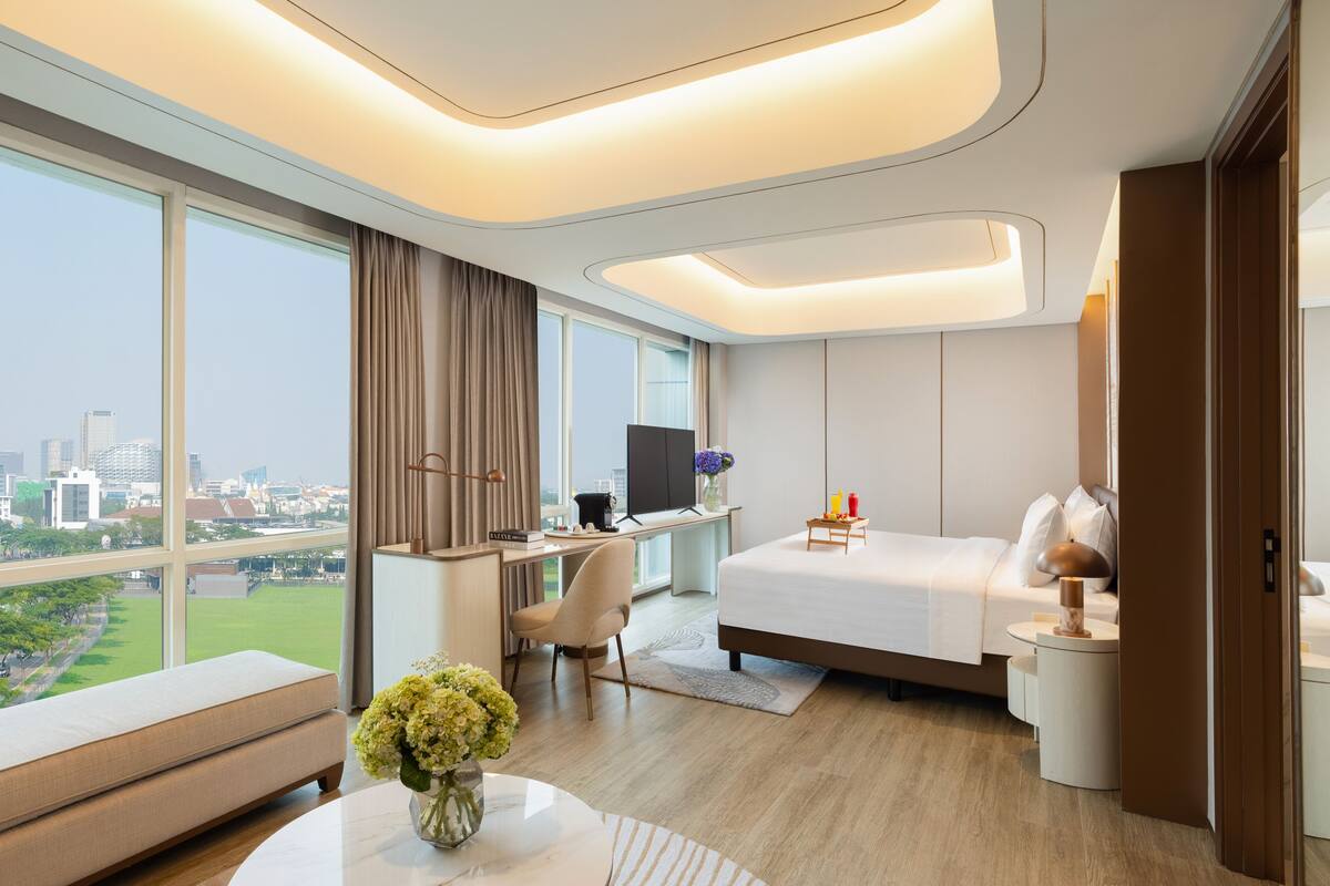 Een moderne hotelkamer met een groot raam, een bureau, een bed en uitzicht op de stad.