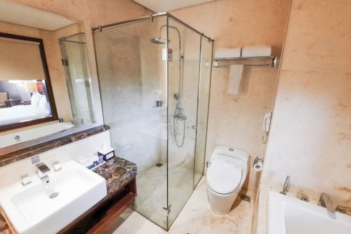 Un baño con ducha envuelta en cristal, inodoro y lavamanos.