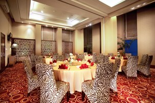 Un salón de banquetes con mesas redondas, sillas estampadas y piso cubierto de alfombra roja.