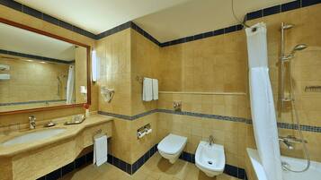 A bathroom with a sink, bidet, toilet, and shower.