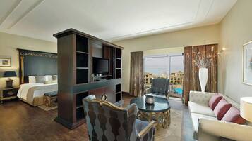 A hotel room with a bed, a TV, a sofa, a chair, and a view of the city.