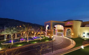 A hotel with a pool, palm trees, and a mountainous backdrop. - Crowne Plaza Jordan Dead Sea Resort & Spa by IHG (Sweimeh)
