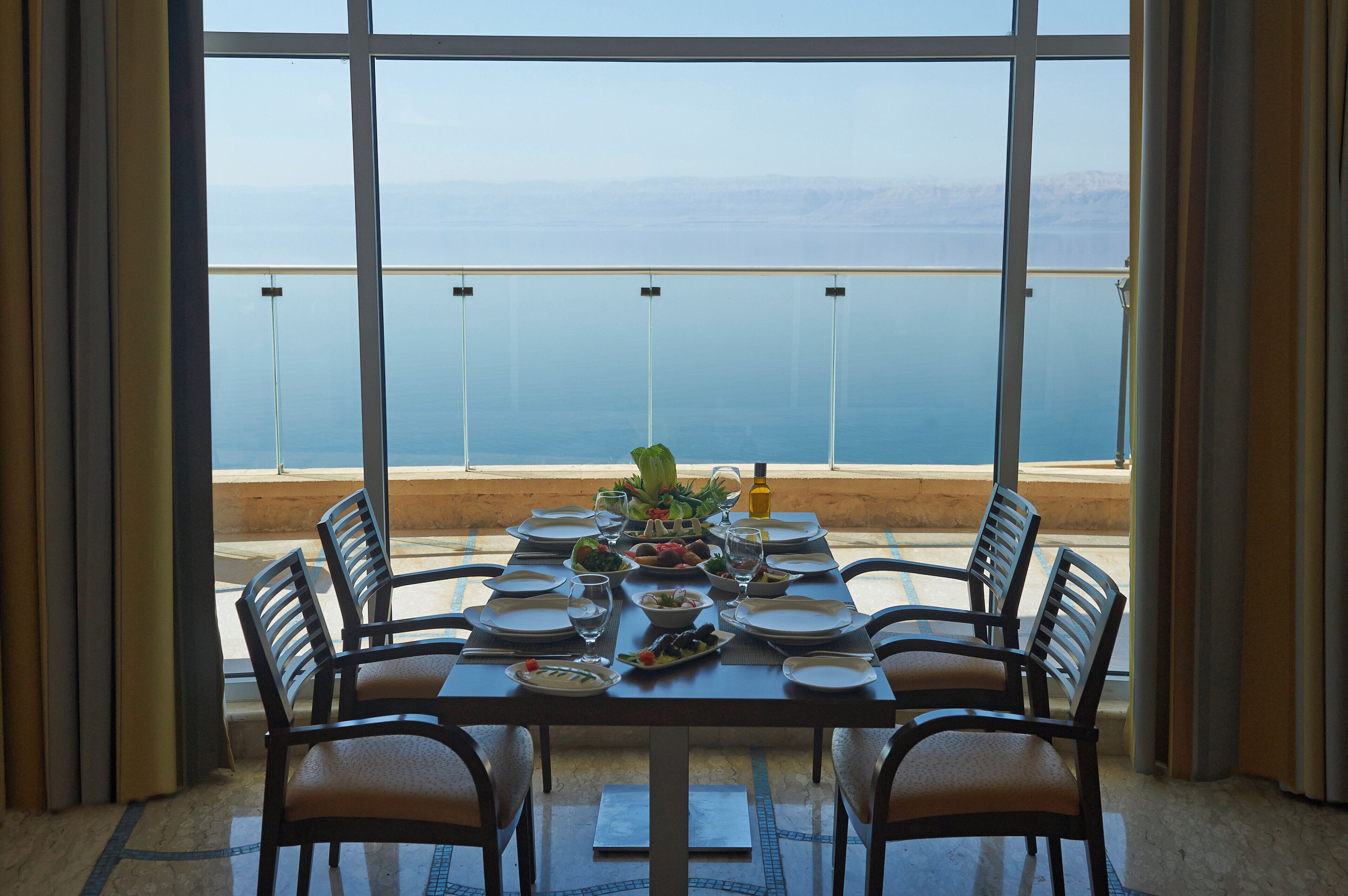 A dining table set for six with a view of the sea.