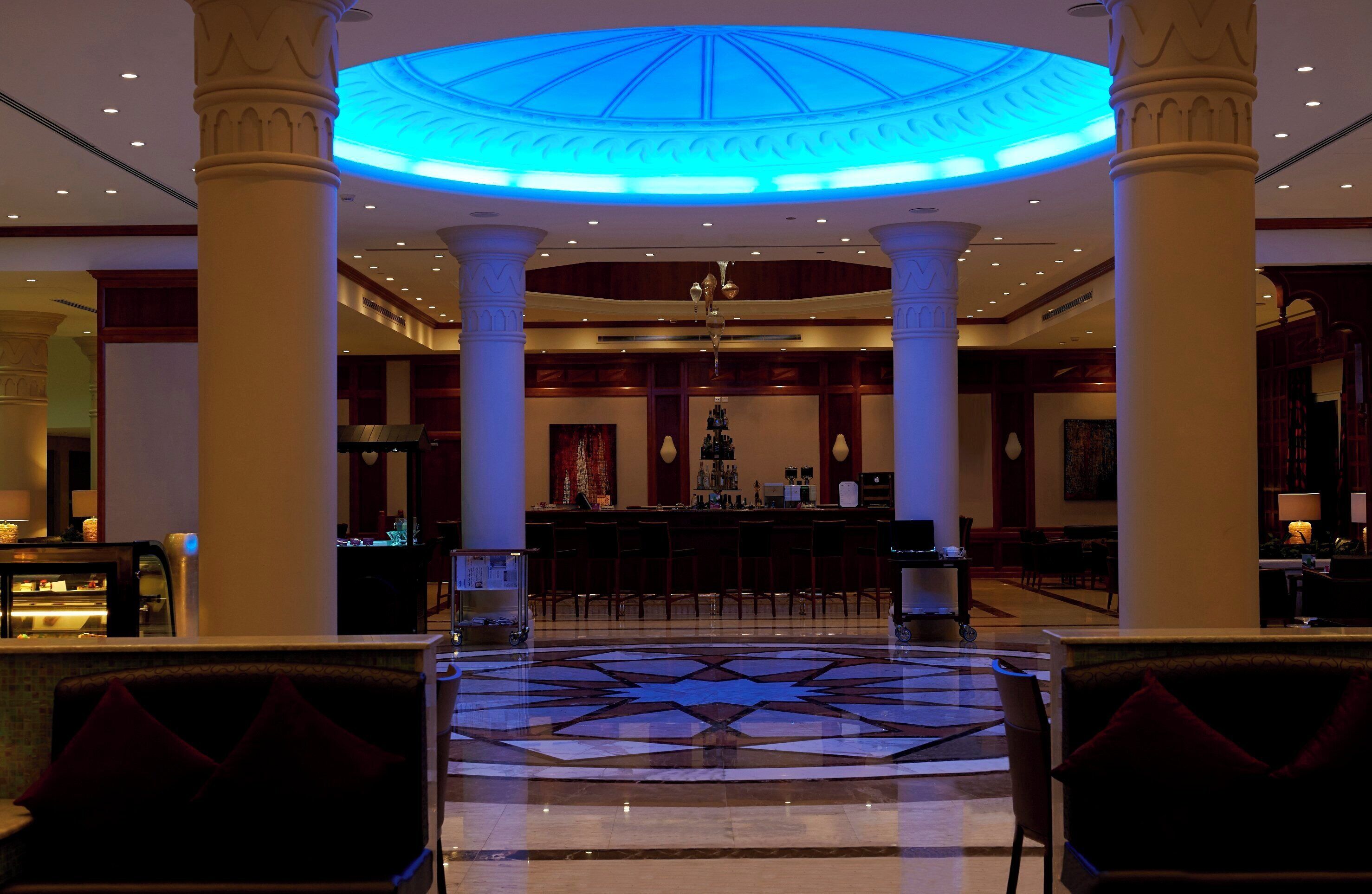 A lobby with a central bar, seating area, and a patterned floor.