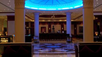 A lobby with a central bar, seating area, and a patterned floor.