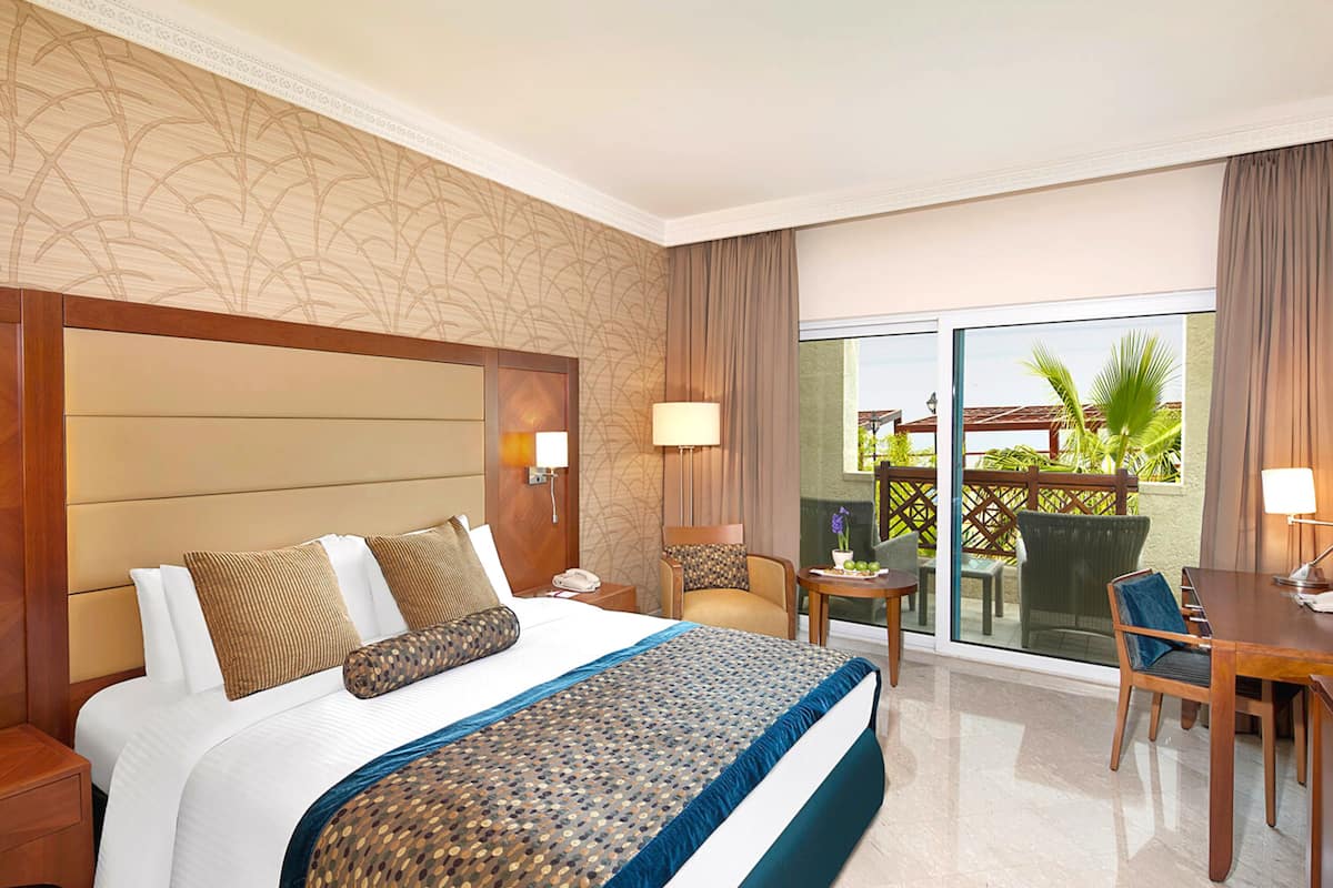 Una habitación de hotel con una cama grande, un escritorio y un balcón con vistas.
