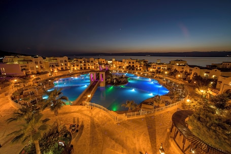 A resort with multiple swimming pools, a central water feature, and a surrounding landscaped area.