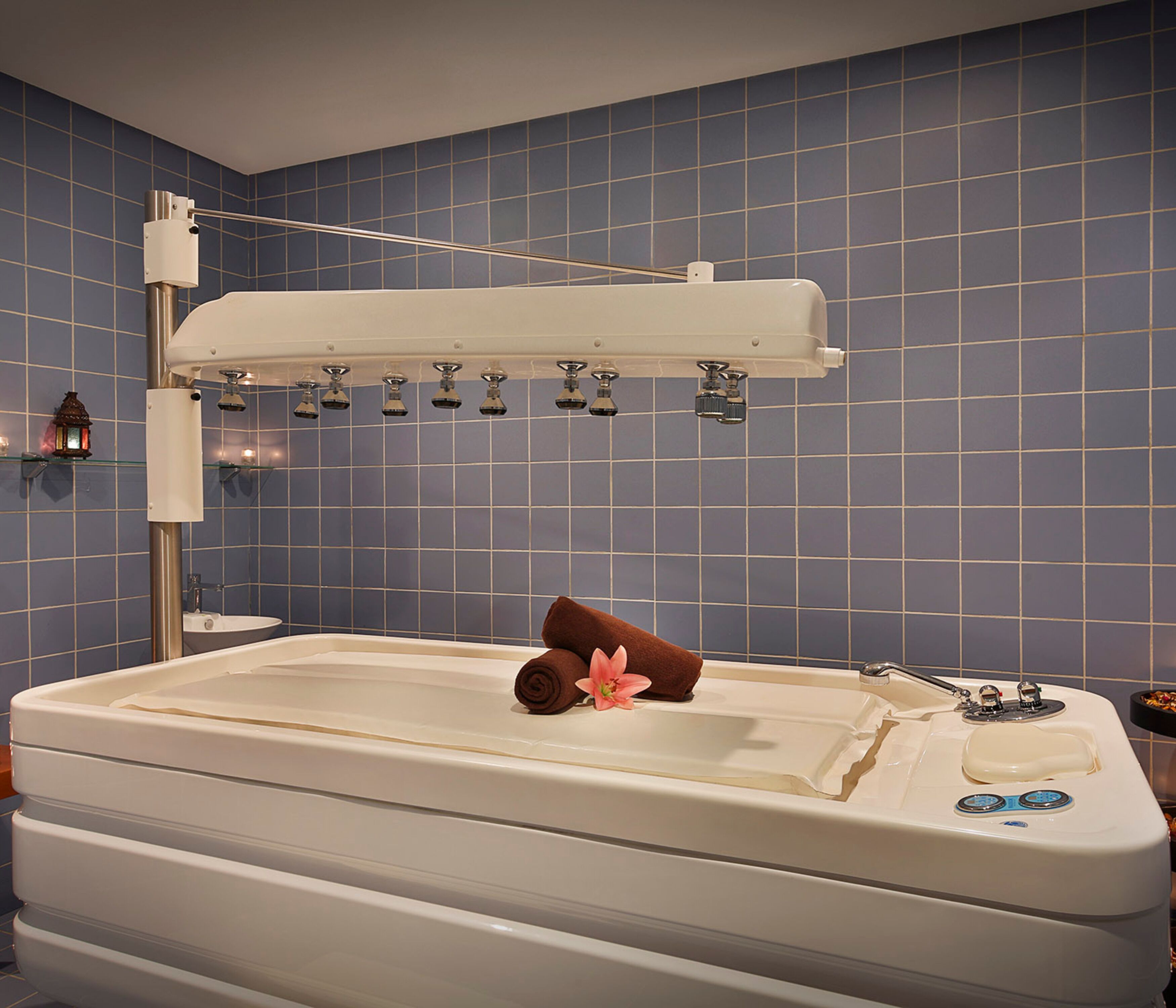 Una vasca da bagno con una doccetta, un asciugamano e un fiore.