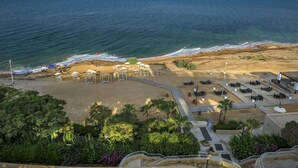 Un hotel frente a la playa con terraza, piscina y vistas al océano.