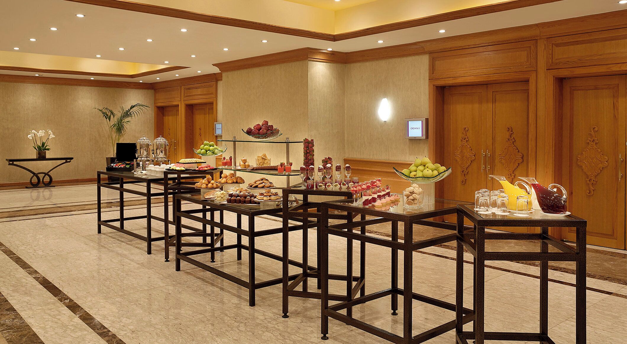 Ein Hotelkonferenzraum mit mehreren Tischen, auf denen ein Buffet aufgebaut ist, mit verschiedenen Speisen und Getränken.