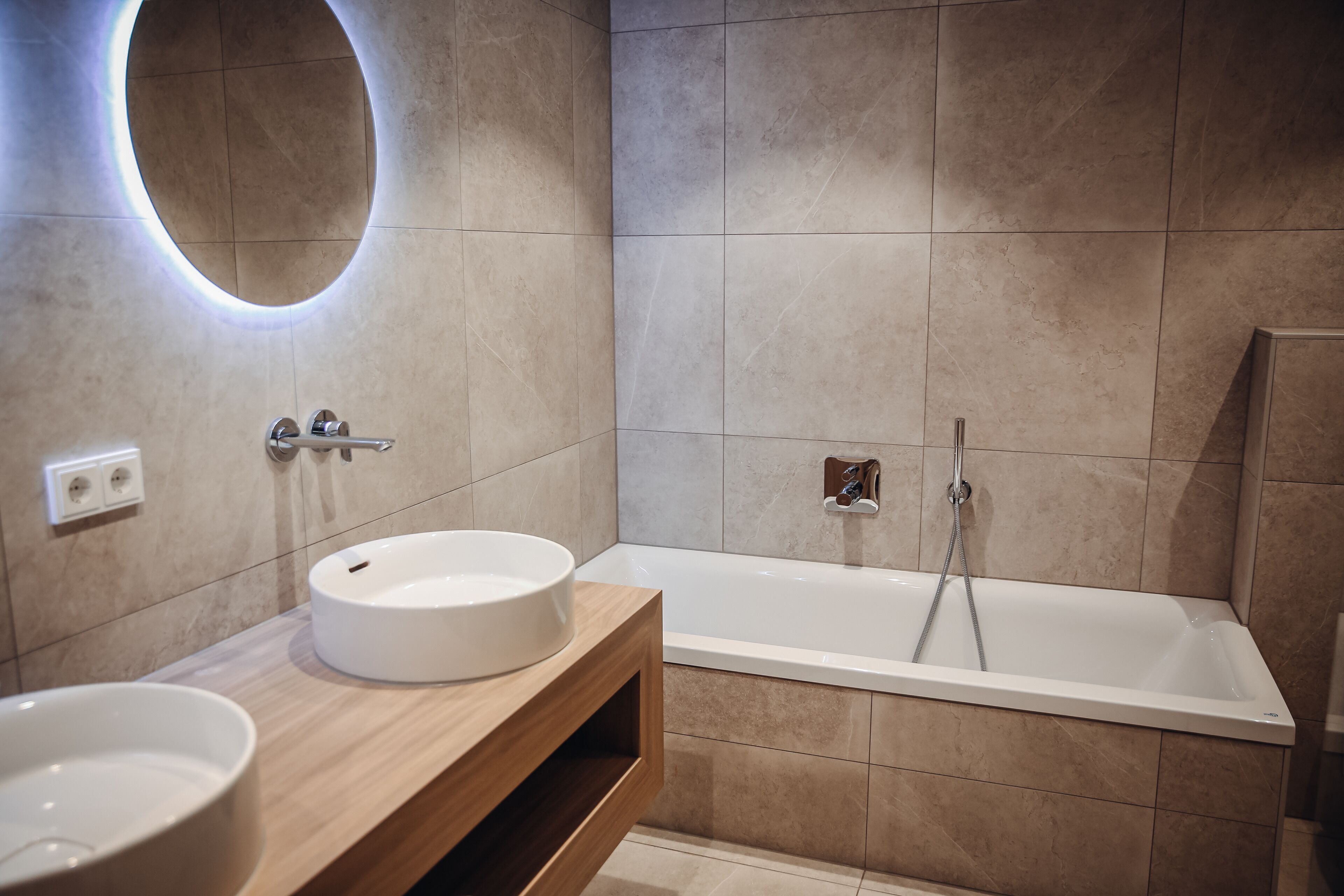 Un baño moderno con dos lavamanos, una bañera y un mueble de tocador de madera.