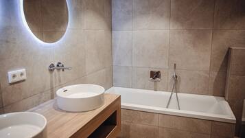 Un baño moderno con dos lavamanos, una bañera y un mueble de tocador de madera.