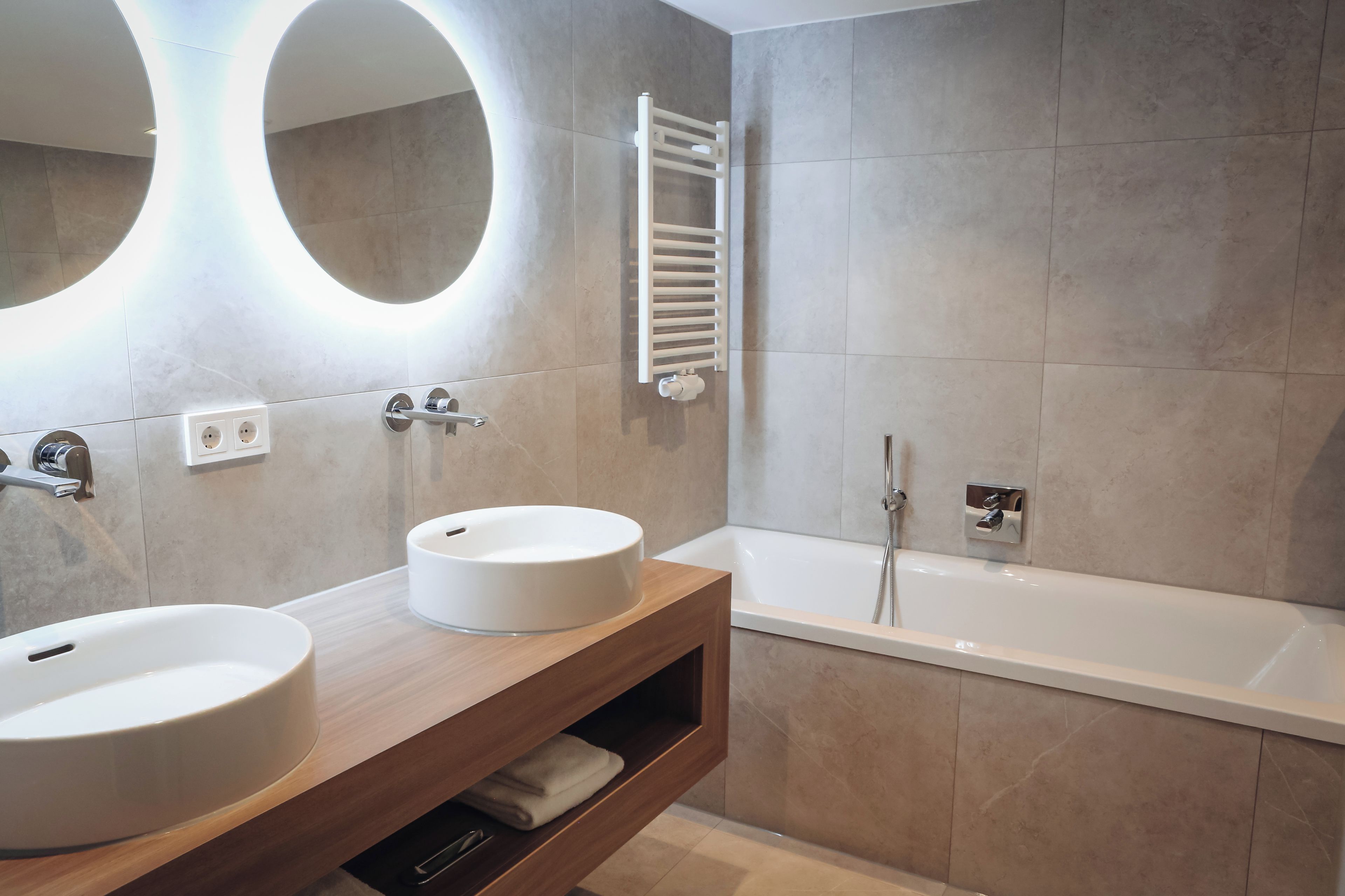 Un baño moderno con dos lavamanos, una bañera y un perchero para toallas.