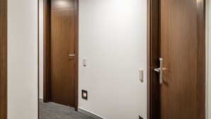A hallway with wooden doors and a carpeted floor. - Hotel Madanis Liceo (L'Hospitalet de Llobregat)