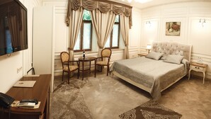 A hotel room with a large bed, a desk with a telephone, a chair, a small table, and a television mounted on the wall. - Chopin Hotel (Lviv)