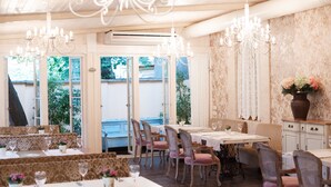 A dining area with multiple tables and chairs, chandeliers, and a view through large windows. - Chopin Hotel (Lviv)