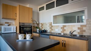 Una cocina moderna con armarios de madera, un microondas, una estufa y un lavamanos.