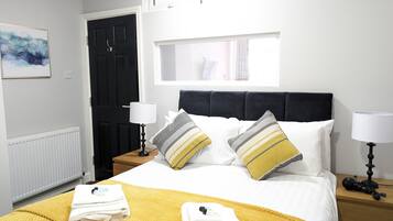 A neatly made bed with a yellow blanket, two pillows with stripes, and folded towels on the bed.