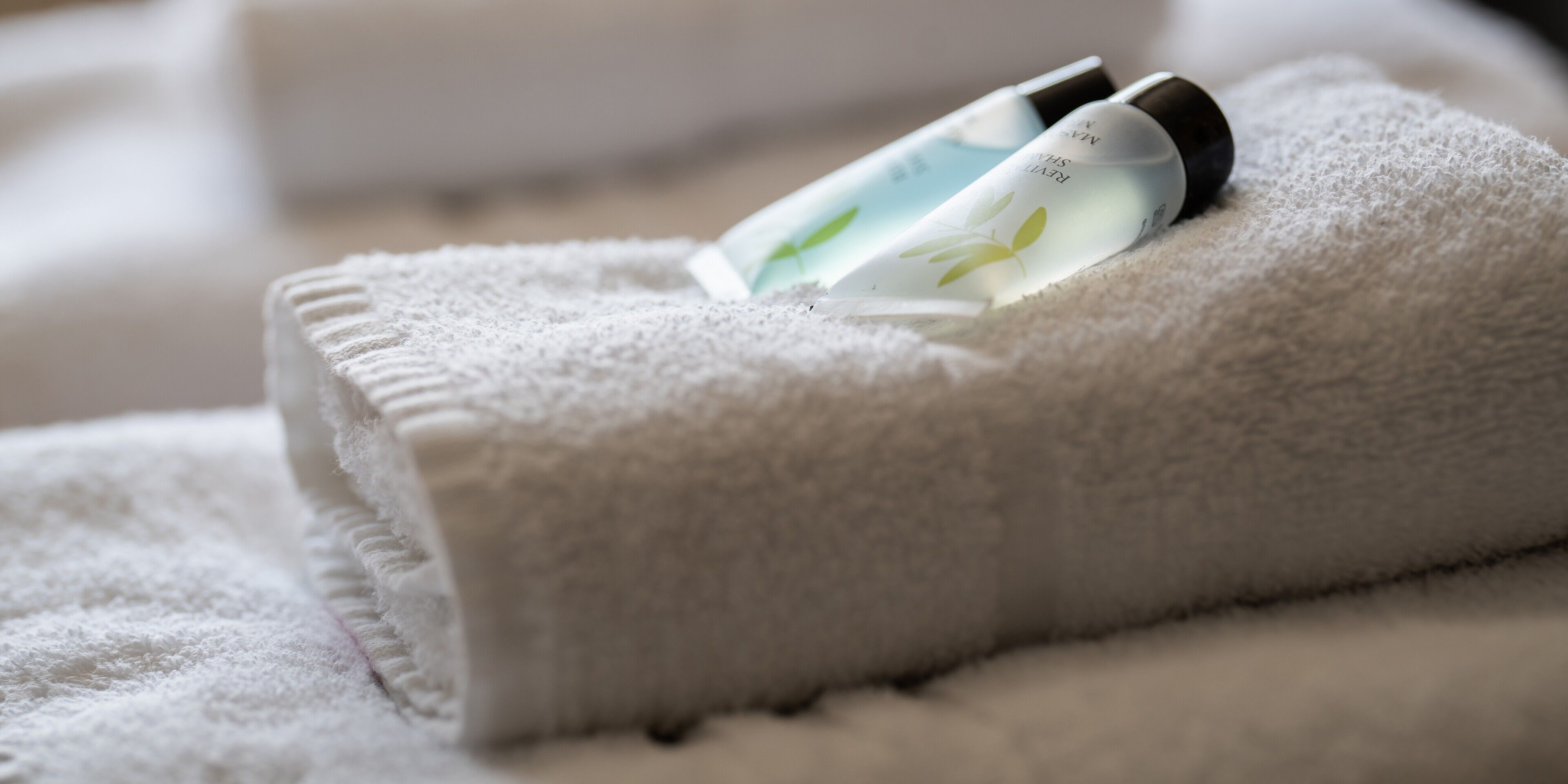 A neatly folded white towel with two bottles of lotion placed on top.