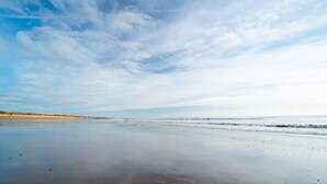 Una playa con una amplia orilla de arena y olas suaves.