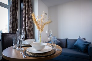 A dining table set with a bowl, wine glasses, and a vase with dried plants. - Coasters Hotel & Apartments (Skegness)