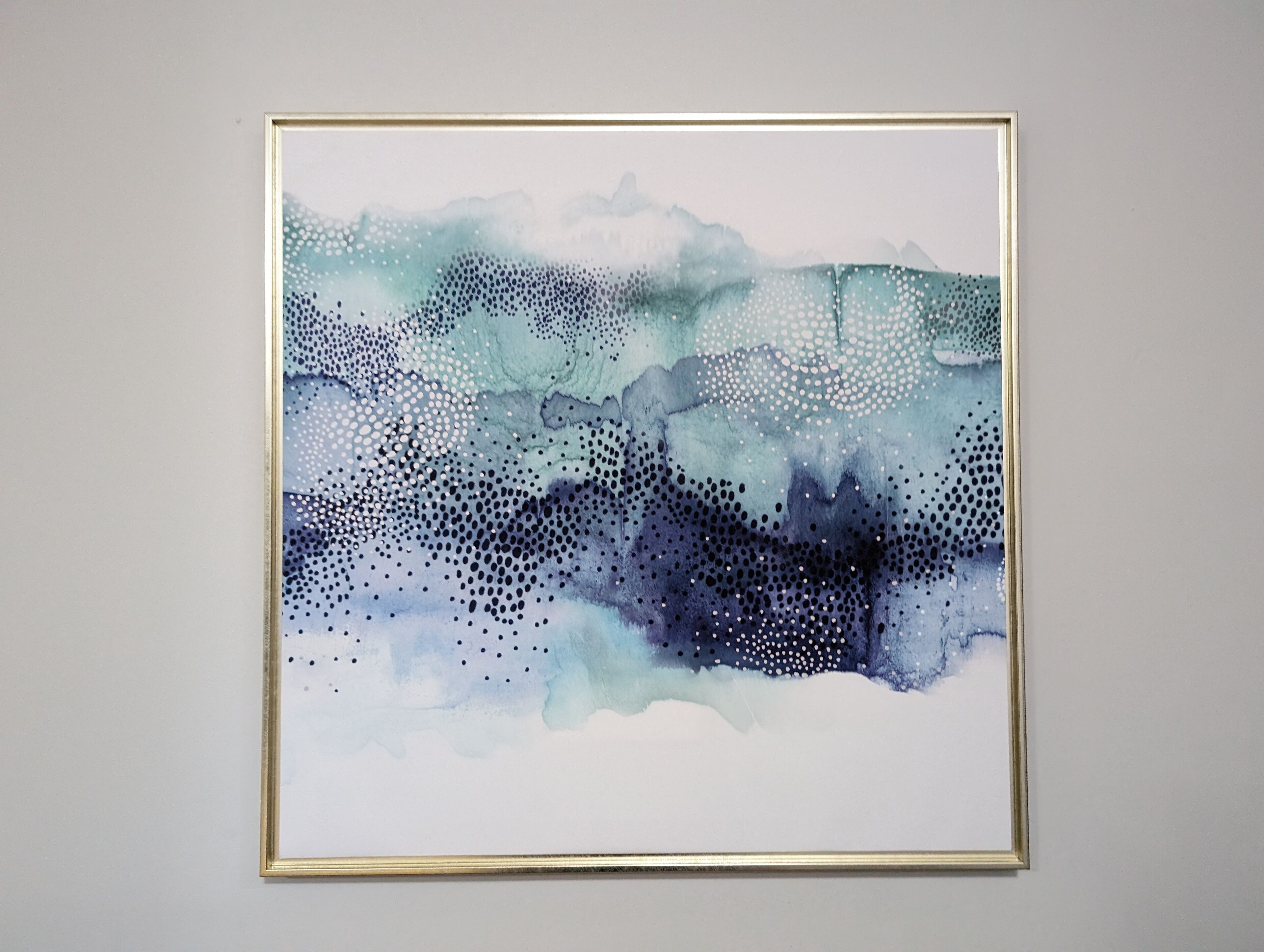 Un quadro astratto incorniciato con sfumature di blu e bianco.