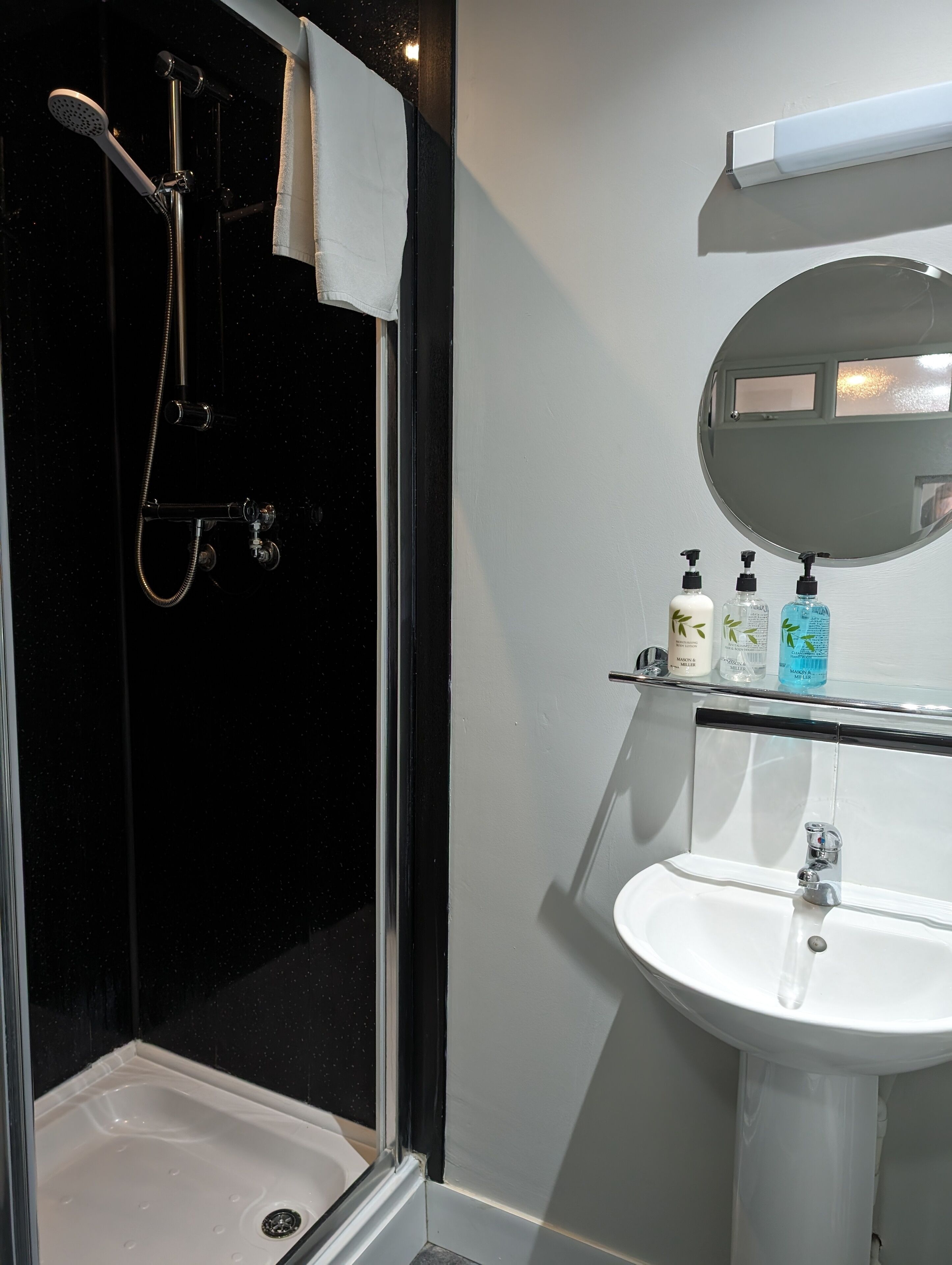 Une salle de bain moderne avec une douche à parois de verre, un lavabo blanc et un miroir au-dessus.